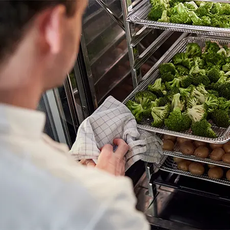 chef pulling out freshly cooked broccoli out of a frijado GO combi oven